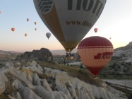 Two hot air balloons drift close by the top of chimney-like rock formations