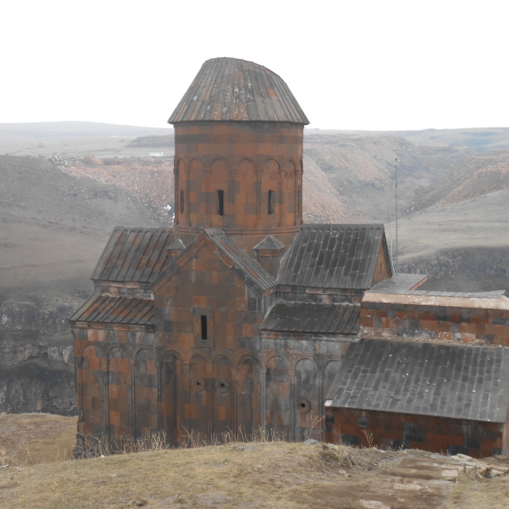 Armenian-style church topped by rounded cone atop cliffside in Ani ancient city