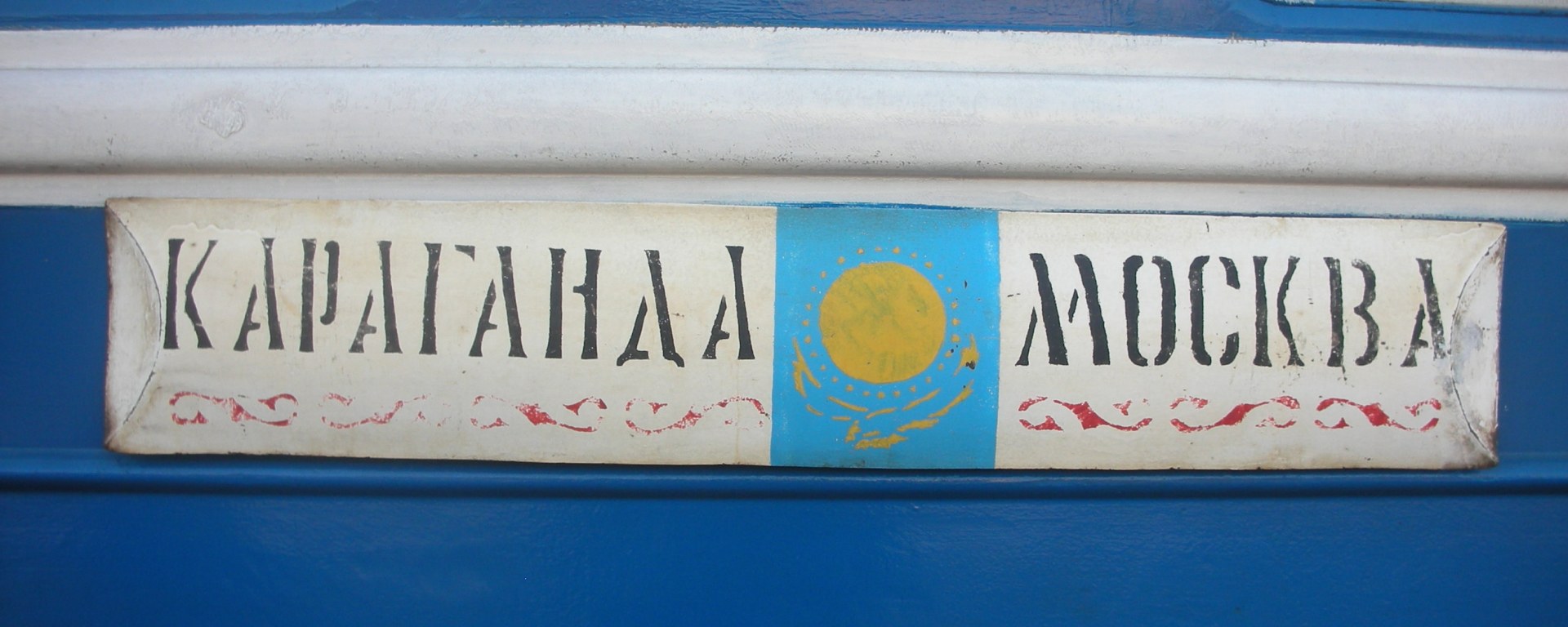 Train sign in Cyrillic letters on side of blue passenger car